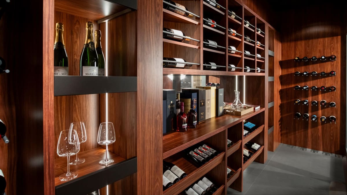 Walnut wine wall with lit shelves, glassware and bottle racks