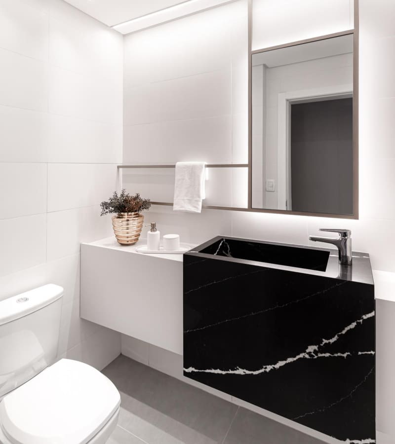 Powder room with a black veined stone sink, a white floating vanity and a backlit mirror