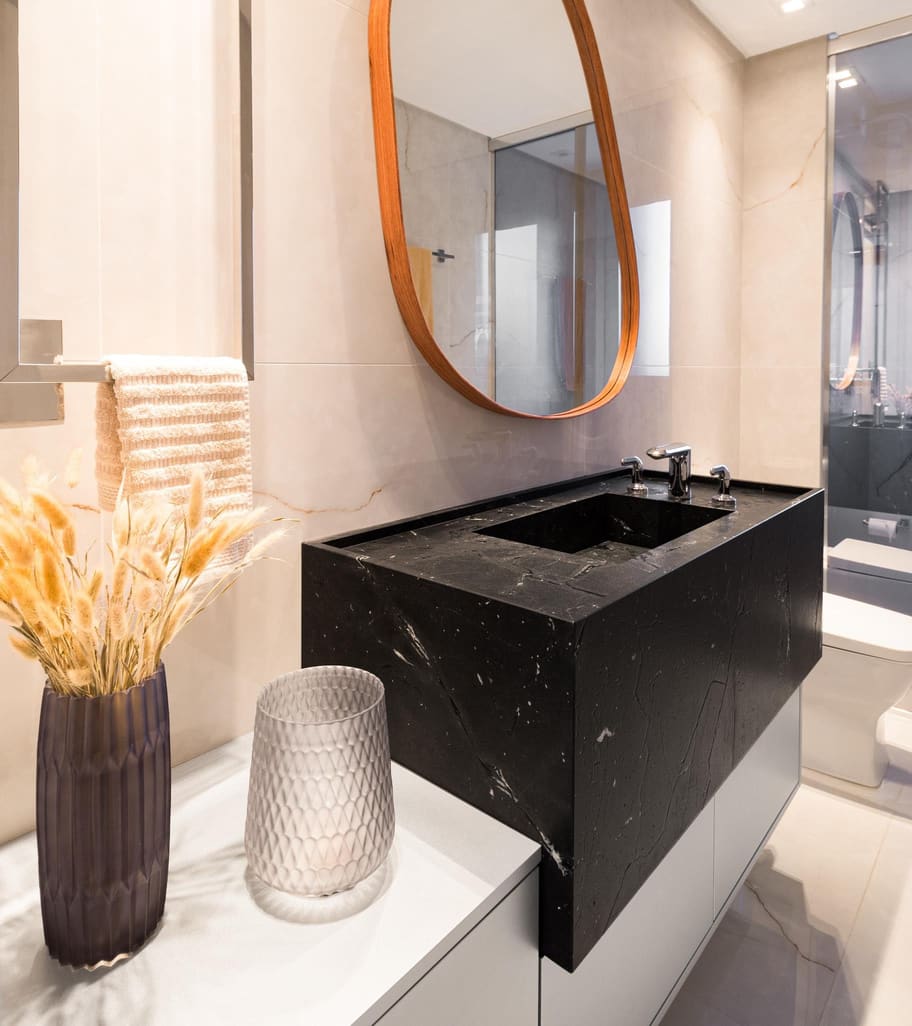 Black stone vanity with a leather-framed oval mirror