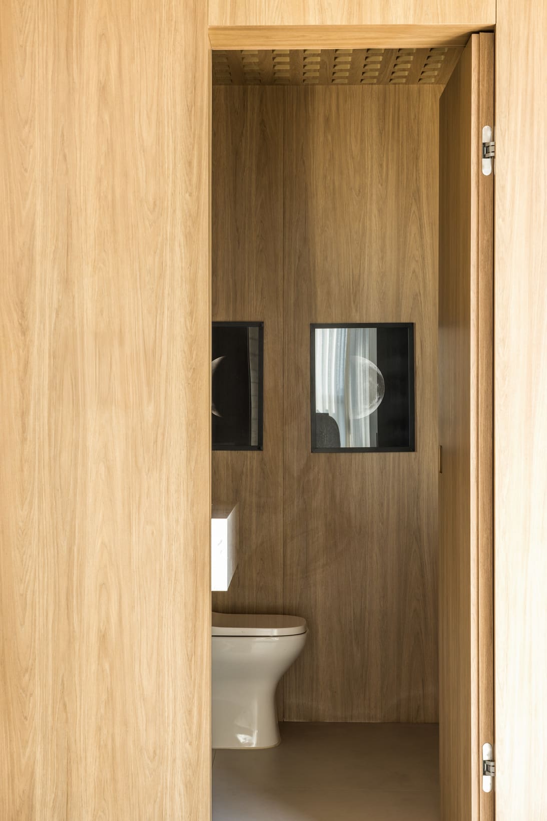 Wood-lined powder room seen through a full-height wood door