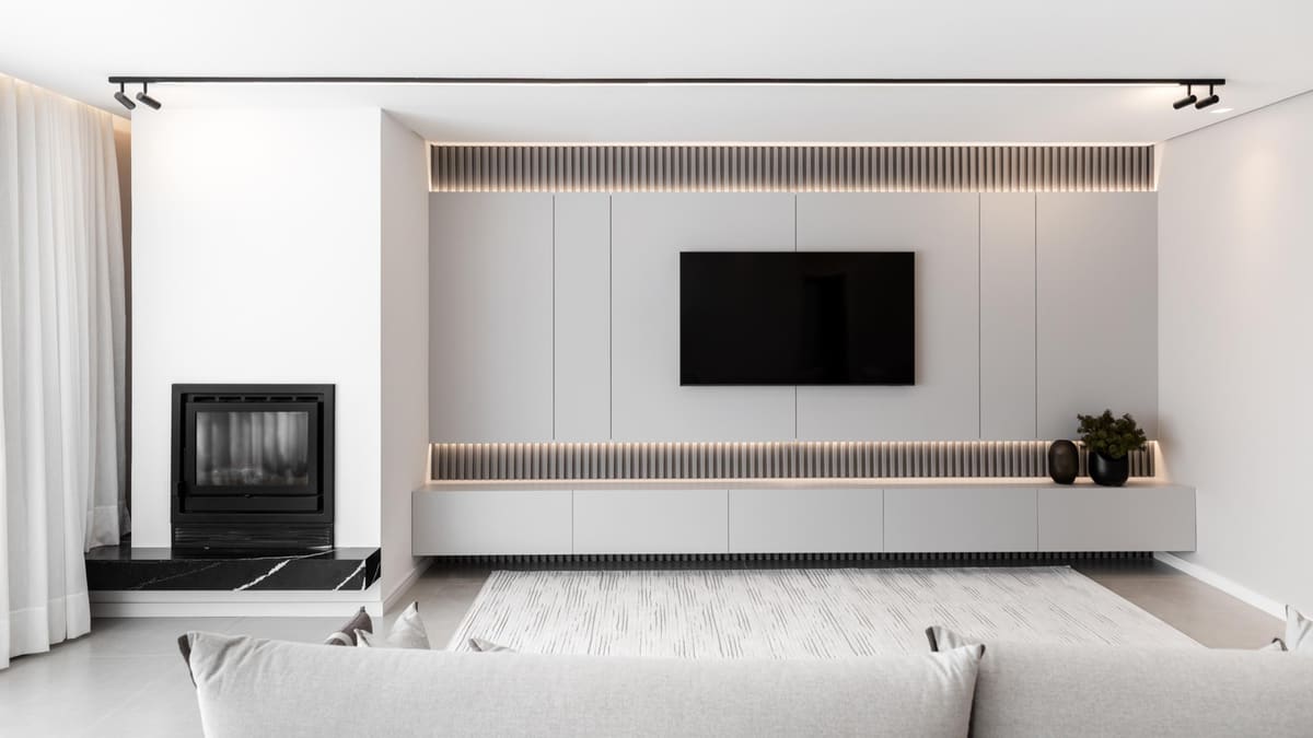 White living room media wall with a lit slatted soffit and a built-in fireplace