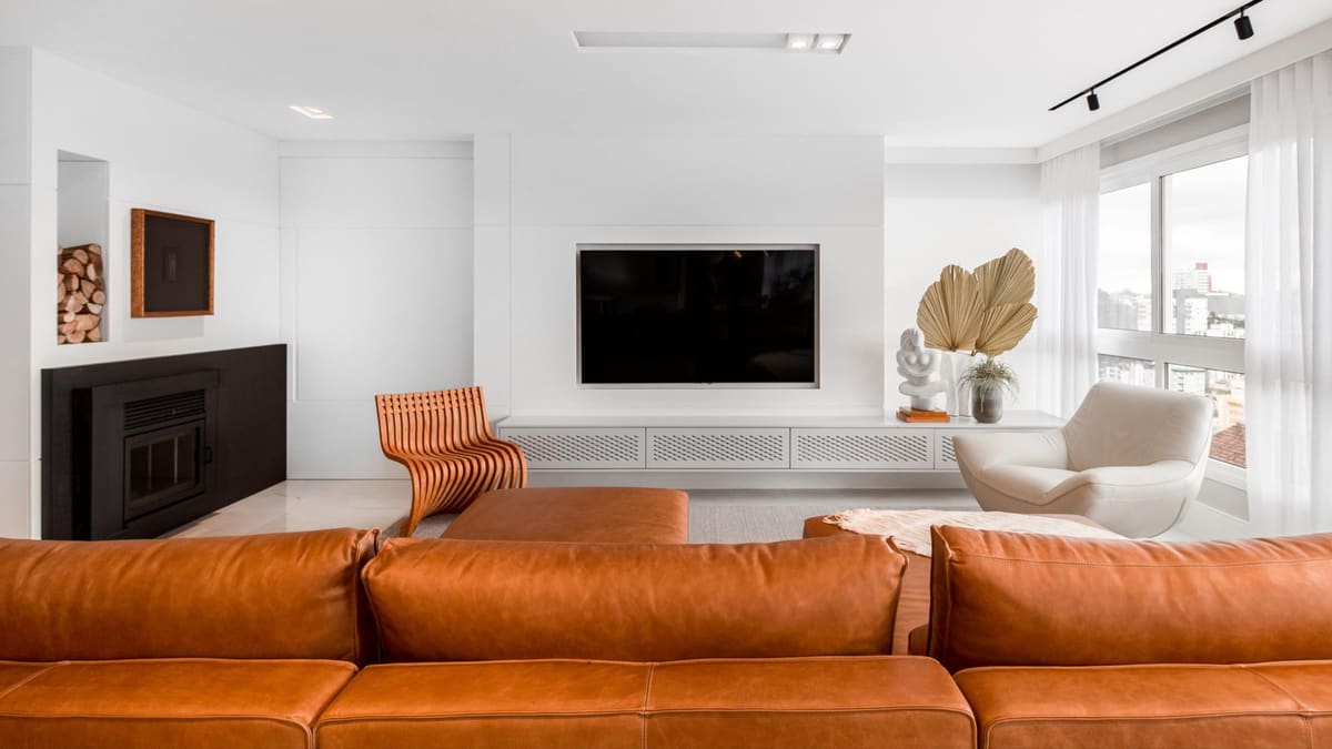 White living room with a leather sofa, a recessed media wall and a log niche by the fireplace