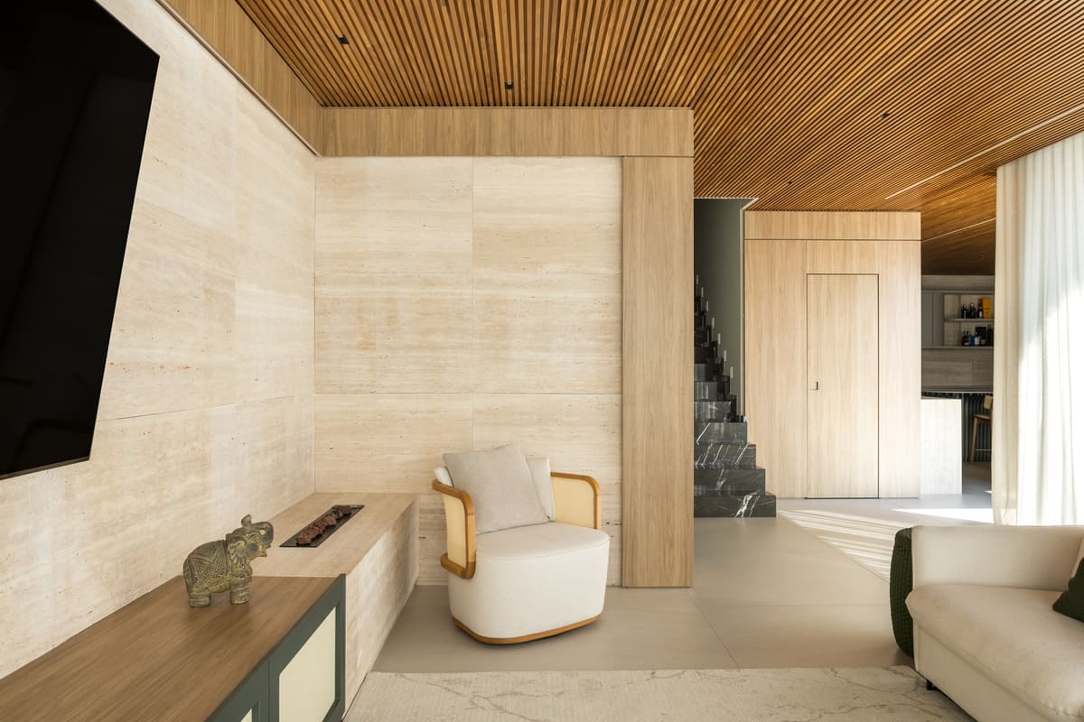 Travertine-clad living room with a slatted wood ceiling and a green cane console