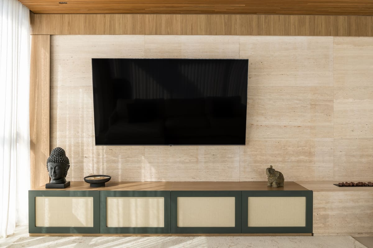 Living room media wall in travertine with a green and cane console and a wood ceiling
