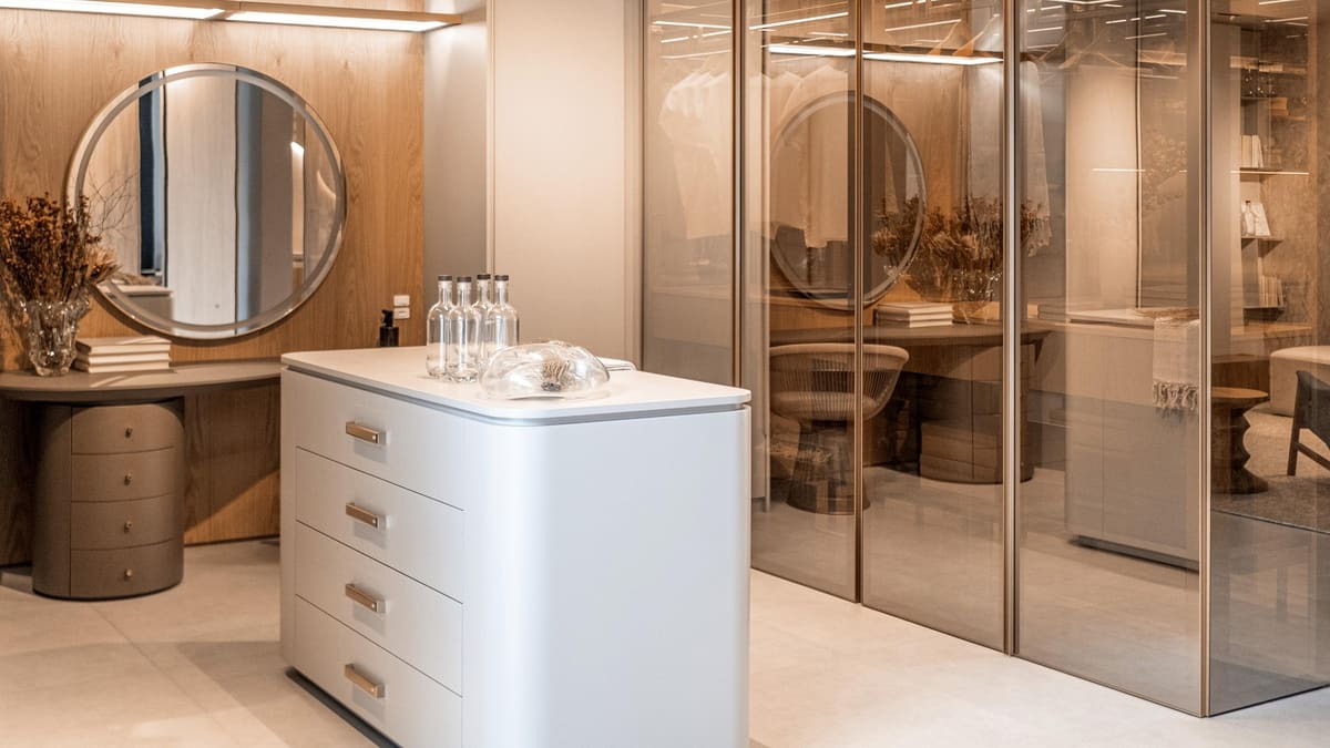 Dressing area with a round mirror vanity, a white island and smoked glass wardrobes