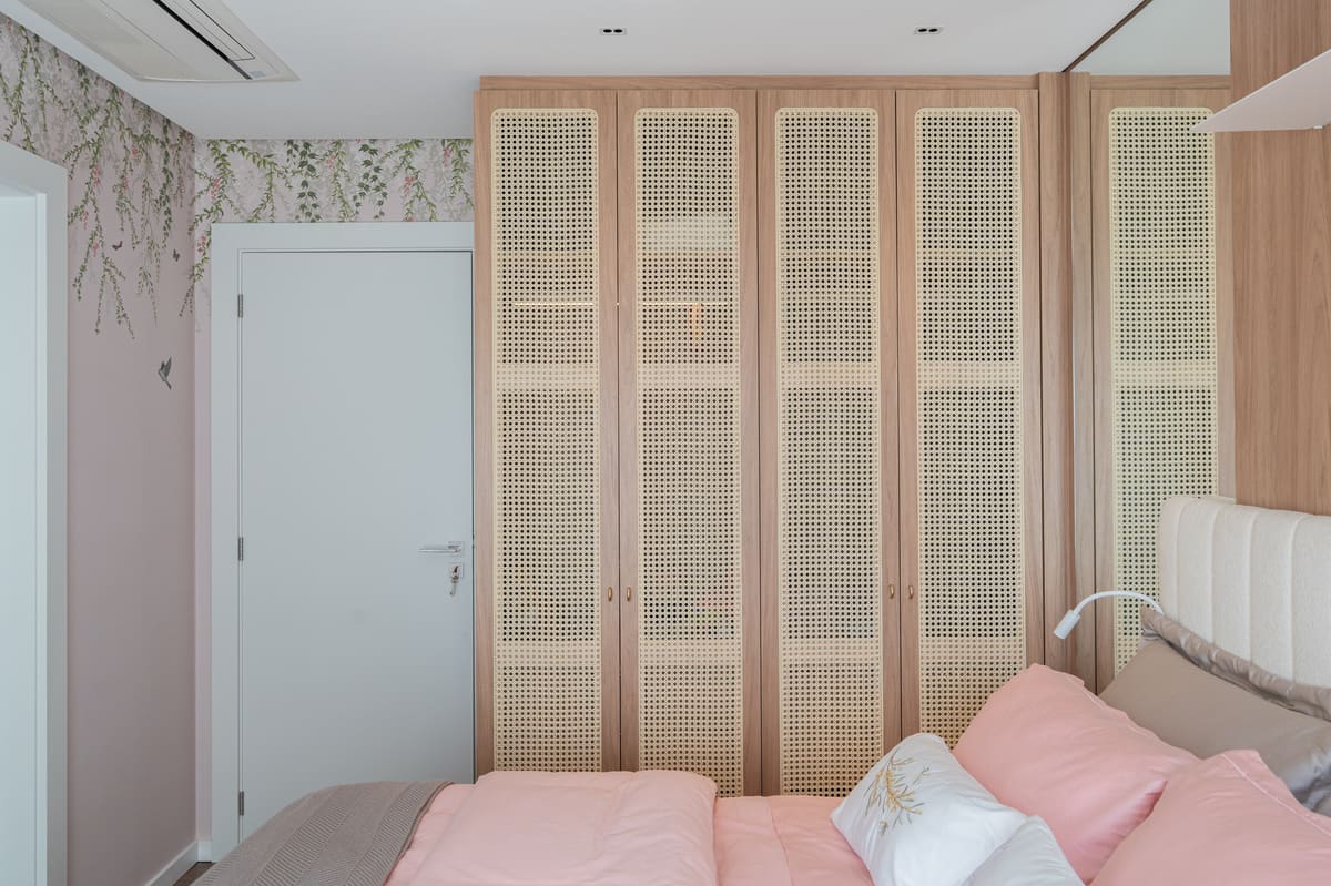 Bedroom wardrobe with cane-panel doors beside botanical wallpaper