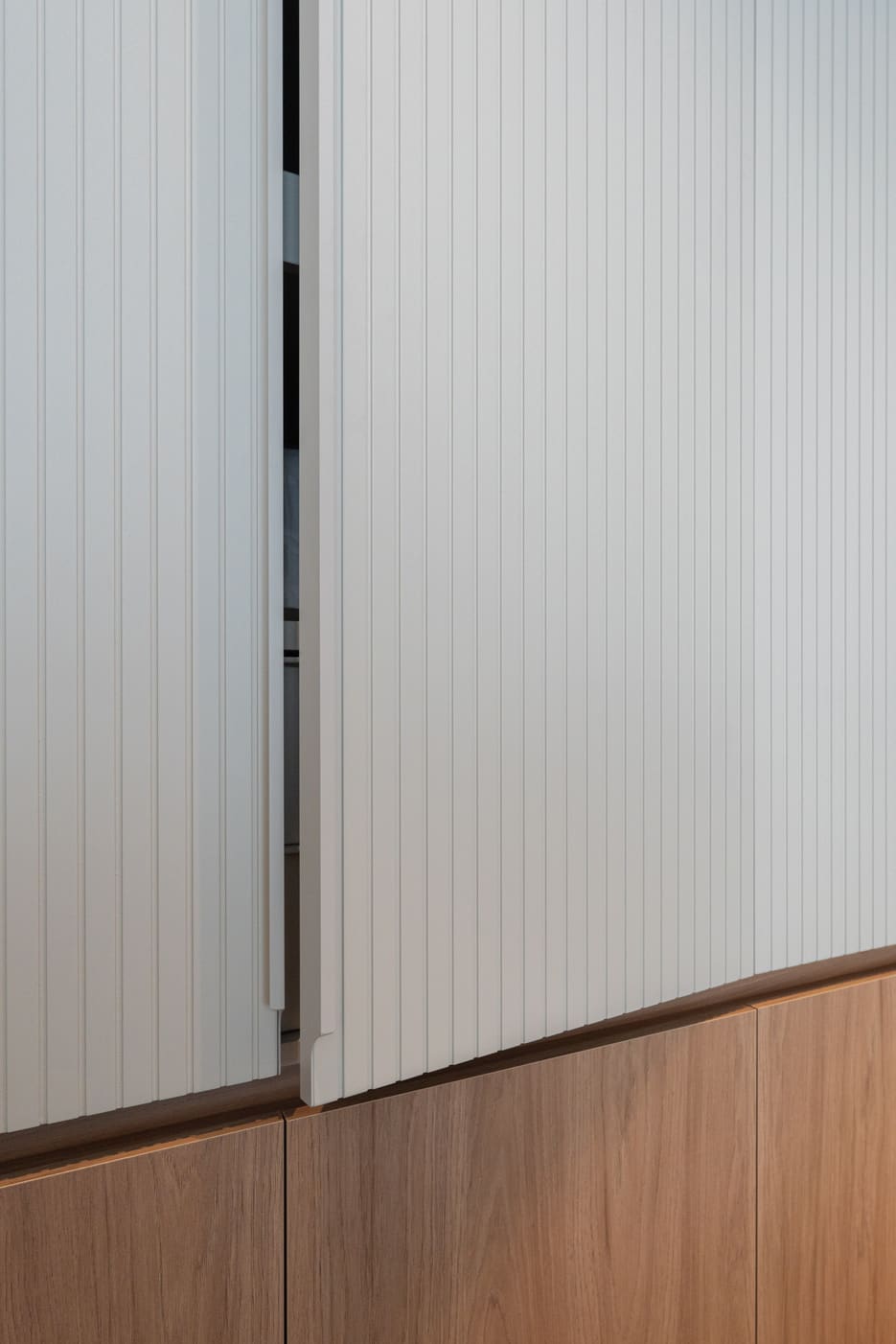 Fluted white wardrobe door meeting a wood base