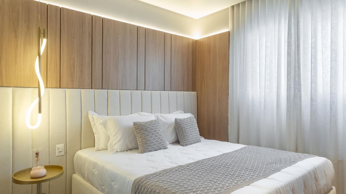 Bedroom with a wood-paneled wall, an upholstered headboard and a sculptural wall light