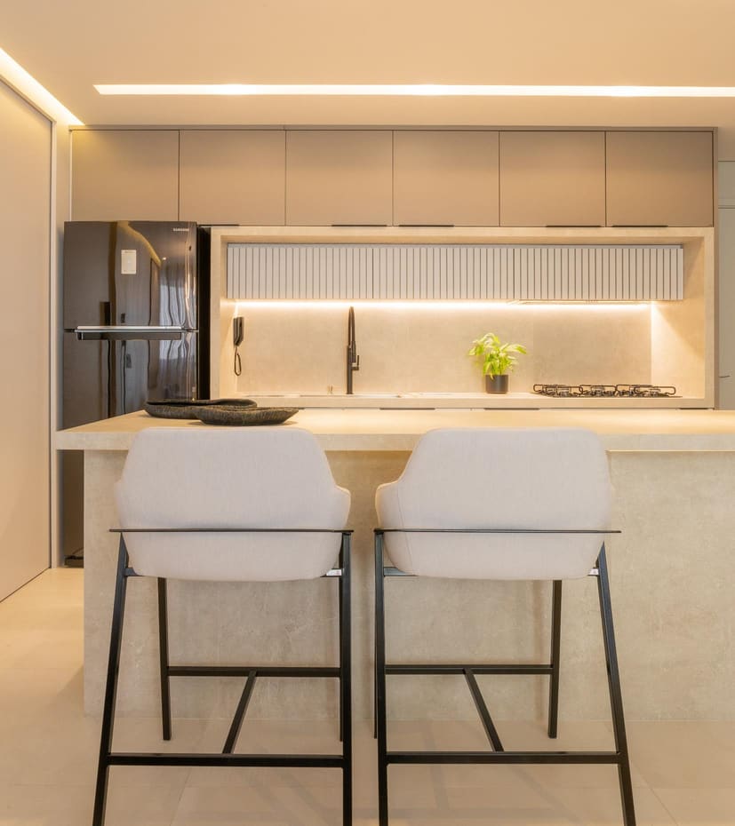 Beige kitchen with a fluted backsplash niche and upholstered bar stools