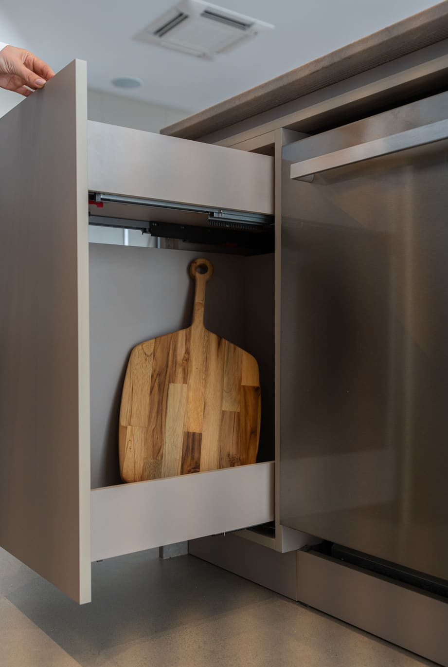 Narrow pull-out cabinet holding a wood cutting board
