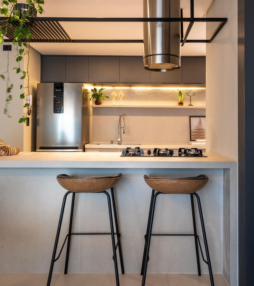 Compact kitchen bar with a stainless hood, a lit shelf and leather stools